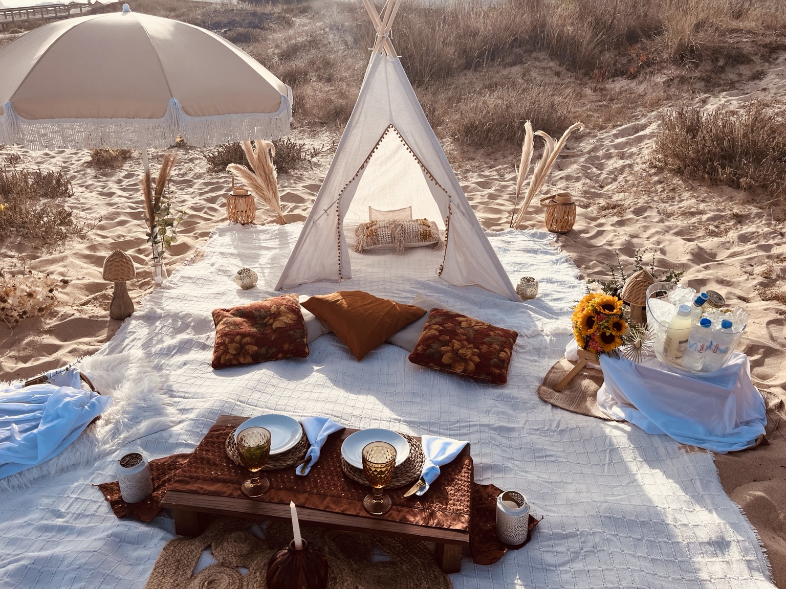 Piquenique na praia com tipi e almofadas